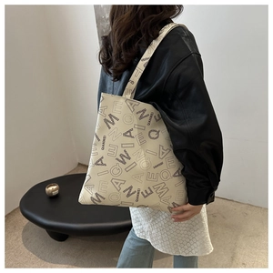 Detail shot of a beige tote bag featuring black artistic typography and QIANWEI branding