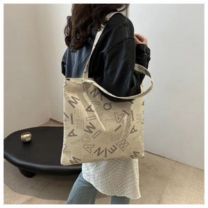 Close-up of a cream tote bag featuring minimalist black letter prints on durable fabric