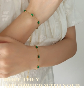 Detail of gold titanium steel bracelet with emerald zircons on a model's wrist