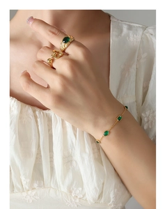 Detail of vintage gold bracelet and rings set with emerald green zircon on model