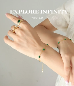 Close-up of vintage gold titanium bracelet and rings featuring green zircon stones