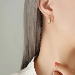 Orecchini a U in titanio dorato con zirconi pavé indossati da una modella di profilo