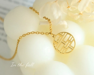 Detailed view of a gold-plated stainless steel necklace with a hollow 'Double Happiness' charm