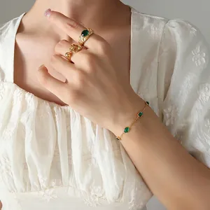 Gold-plated titanium bracelet and emerald zircon rings set on a female model
