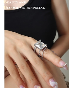 Detailed close-up of a silver ring with large square zircon and decorative chain link