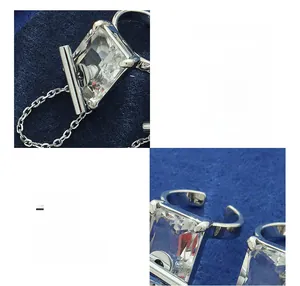 Macro detail of silver ring with large rectangular zircon and chain tassel embellishment