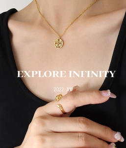Detailed close-up of a golden Xi character pendant necklace and a minimalist open ring