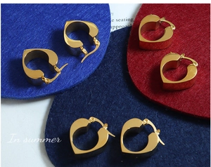 Detailed macro view of three pairs of chunky gold heart hoop earrings with mirror finish