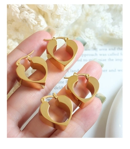Close-up of four vintage gold heart earrings displayed on a hand with lace background