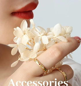 Detail of gold titanium rings with colorful zircon inlays on hand with dry flowers
