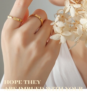 Detail of a minimalist gold ring with colored zircons worn on a hand with dried flowers