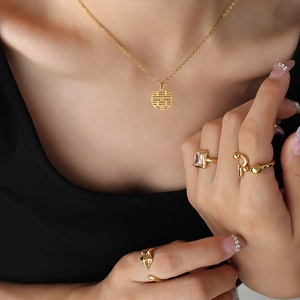 Golden Xi character necklace and assorted rings set displayed on a model