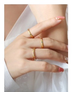 Detail of stacked gold wavy rings with red, green, and white zircon on silk background