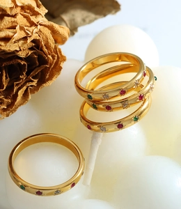 Macro shot of gold vintage rings set with red and green cubic zirconia on white background