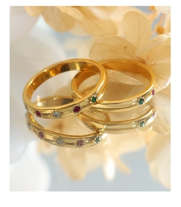 Detailed macro view of gold-plated rings featuring colorful zircons and starburst engravings