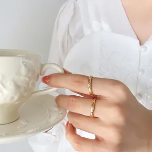 Gold plated stainless steel rings with colorful zircon stones worn by a hand holding a cup