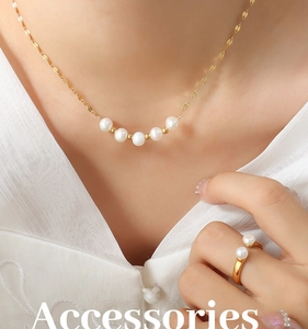 Détail d'un collier doré avec cinq perles et bague assortie sur un mannequin élégant