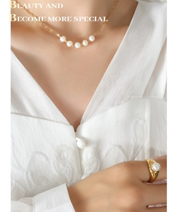 Détails d'une chaîne dorée élégante avec perles blanches et bague assortie sur modèle
