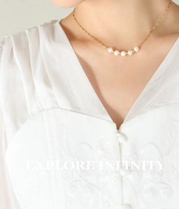 Détail d'un collier doré élégant avec perles blanches et billes d'or sur le cou du mannequin