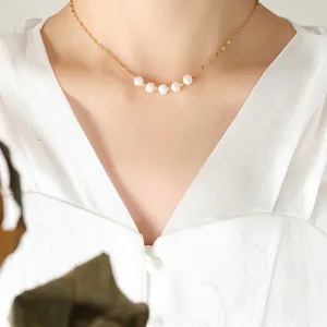 Collier élégant en chaîne dorée avec cinq perles blanches sur un mannequin femme