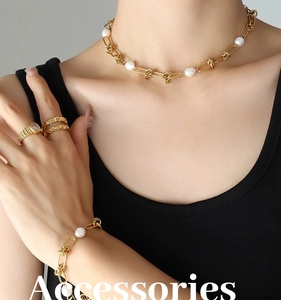 Detail of gold knot chain jewelry set with white pearls on a model wearing black dress