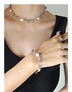 Close-up of pearl chain necklace and bracelet set with tiger eye ring on model