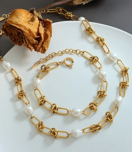 Detailed macro view of gold-plated knot chains and lustrous freshwater pearls in a jewelry set