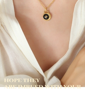 Close-up of gold necklace with black enamel star compass pendant on model collarbone