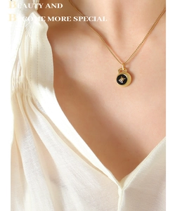 Close-up of a gold star pendant with black enamel on a delicate chain worn by a model