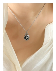 Detail of silver star pendant necklace with black enamel center worn on model