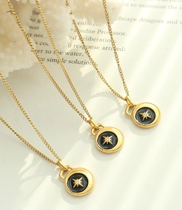 Close-up of gold titanium steel necklaces with black enamel star pendants on white coral