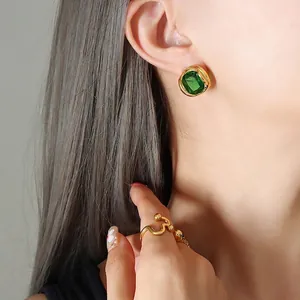 Parure de bijoux dorés avec boucles d'oreilles émeraude et bague minimaliste ondulée