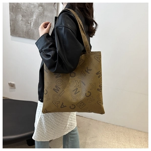 Detail of dark brown tote bag with all-over letter print and sleek shoulder strap