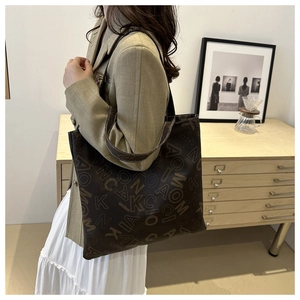 Detail of a large brown tote bag with stylish letter prints and a slim shoulder strap