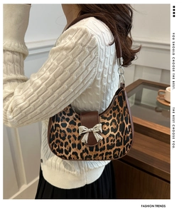 Detail of leopard print underarm bag featuring a silver metal bow and brown leather strap