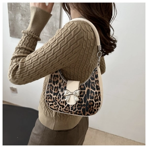 Dettaglio della borsa a spalla leopardata con fiocco d'argento portata sulla spalla