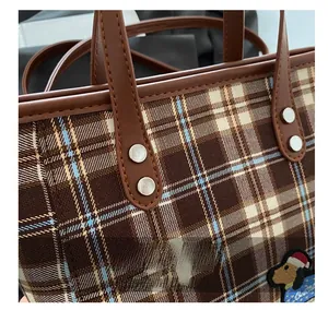 Detail von braunem Karo-Webstoff, Ledergriff mit Nieten und kleiner Welpen-Stickerei