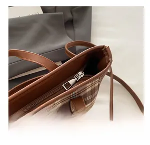 Nahaufnahme des glatten Silber-Reißverschlusses und braunem Karostoff der Handtasche