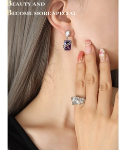 Detail of rectangular purple zircon earrings and textured silver ring worn by a model