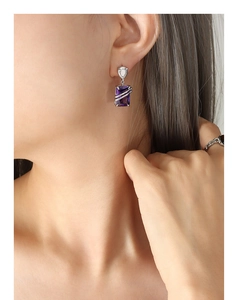 Macro shot of silver drop earring with rectangular purple zircon and metallic wrap