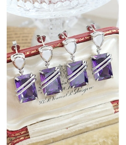 Macro view of purple square zircon earrings with crisscross silver lines in a vintage box