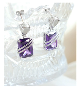 Macro view of rectangular purple zircon earrings with silver-tone metal line accents