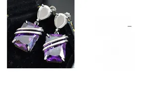 Macro detail of rectangle purple zircon earrings with silver trim in black velvet box