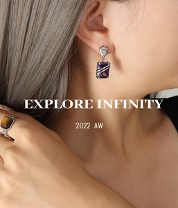 Detail of square purple zircon earrings and a textured tiger eye ring on model