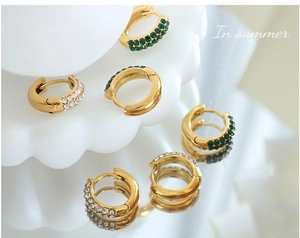 Macro view of 18K gold plated hoop earrings with green and white cubic zirconia stones