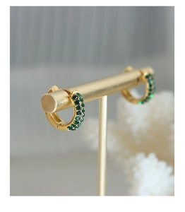 Detail of 18K gold plated hoop earrings featuring three rows of green zircon stones