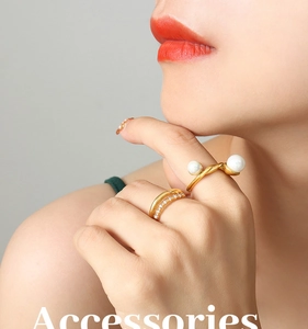 Gros plan de bagues dorées avec perles blanches et cristaux pavés sur la main