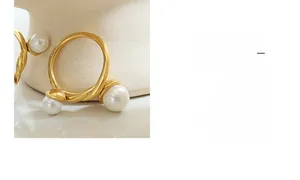 Détail d'une bague torsadée en or avec perles blanches sur un support en céramique
