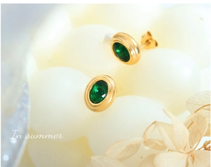 Détail de boucles d'oreilles vintage en or avec zircon vert sur fond floral doux