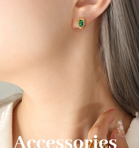 Gros plan de boucles d'oreilles rétro en or avec zircon vert portées à l'oreille